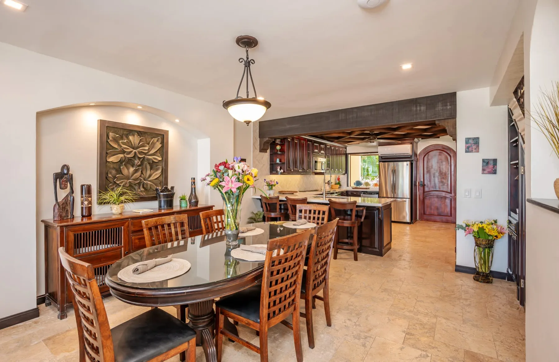 Un comedor abierto con cocina, una mesa amplia y asientos de madera.