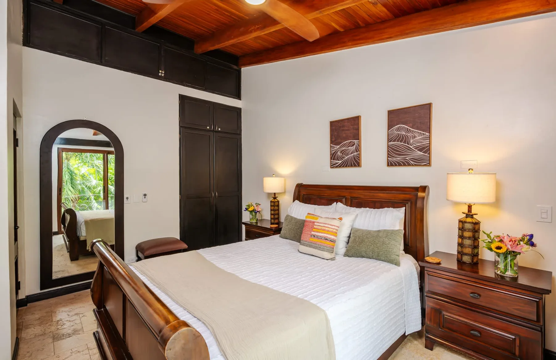 Un dormitorio con una cama de madera, mesitas de noche y un techo alto de madera.