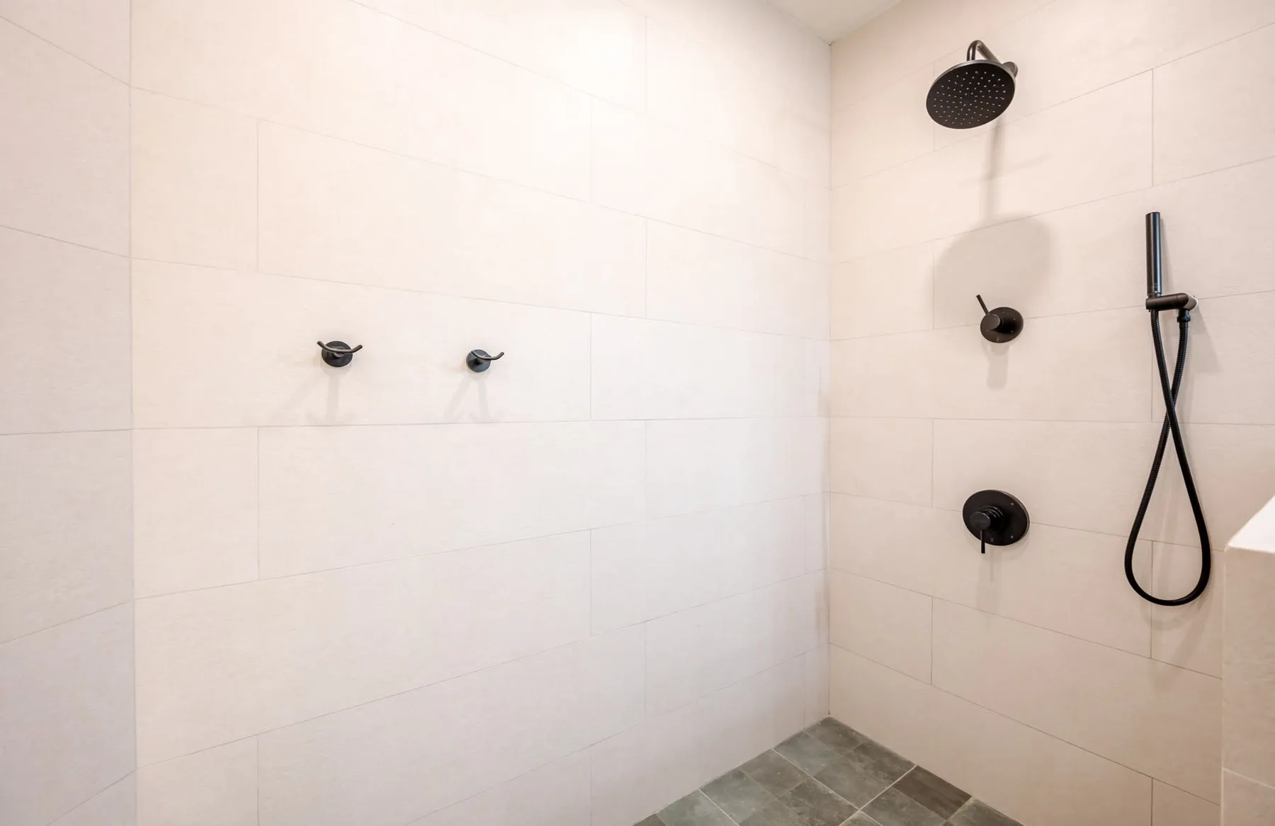 Una zona de ducha con azulejos, rociador superior y ducha de mano.