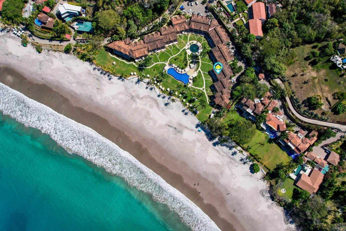 Zona común: Vista aérea de un complejo junto a la playa, con jardines junto al océano.