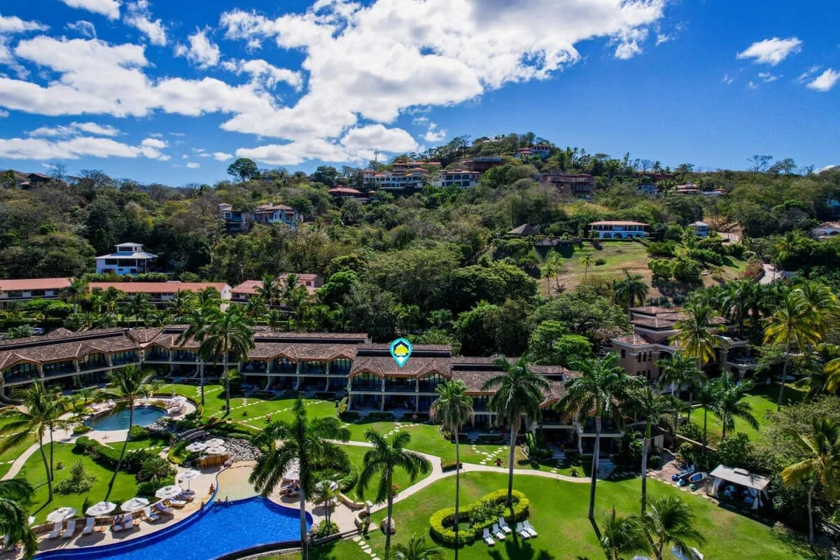 Zona común: Un complejo turístico se encuentra entre colinas verdes, junto a una piscina.