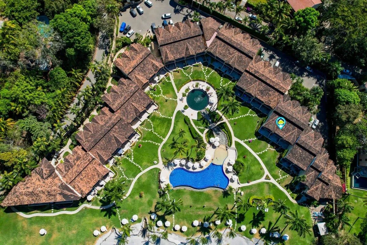 Zona común: Vista aérea de un complejo turístico rodeado de jardines y una piscina.