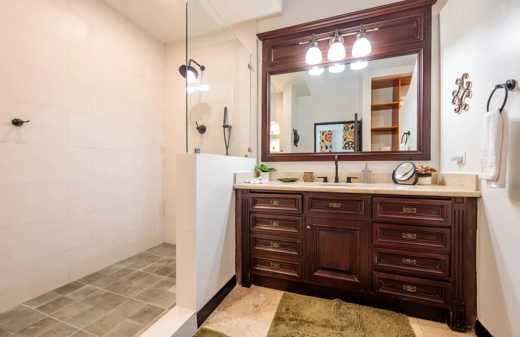 Un tocador de baño con un espejo grande junto a una ducha.