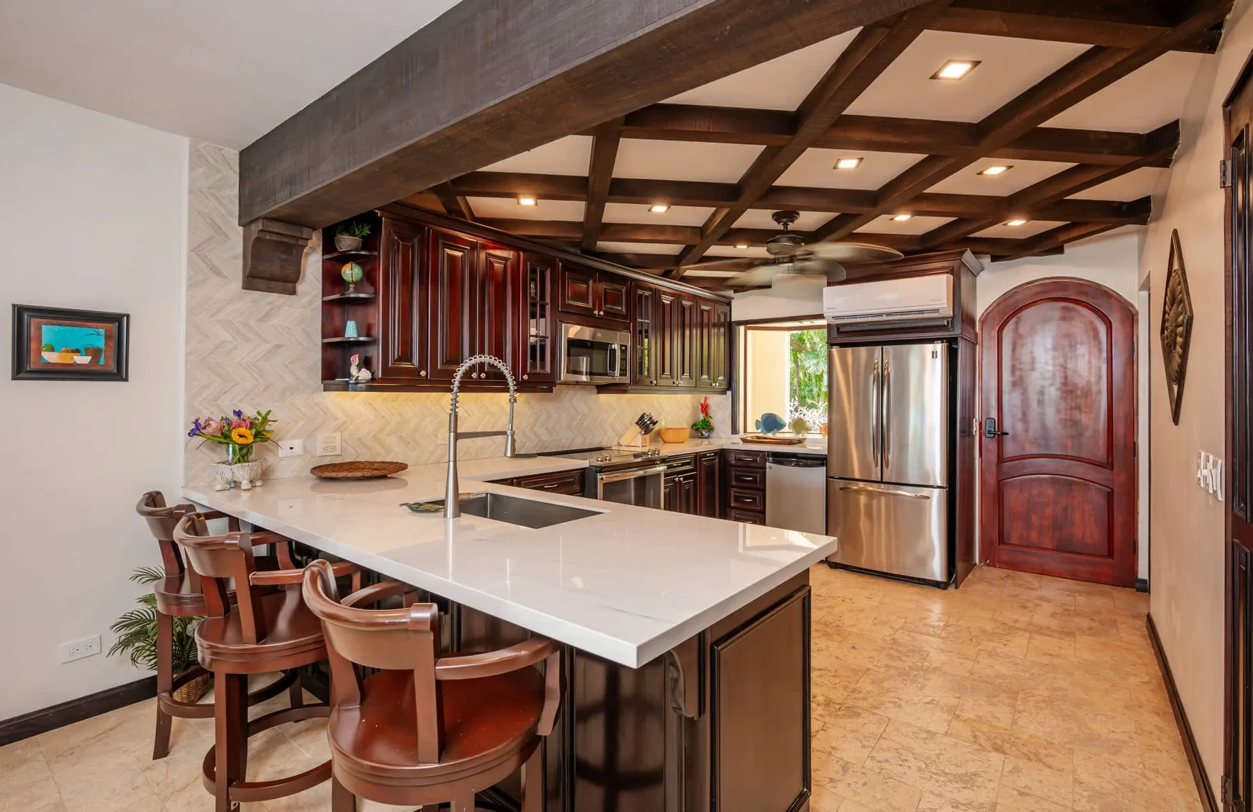Una cocina amplia con gabinetes de madera oscura, una isla grande y asientos de barra.