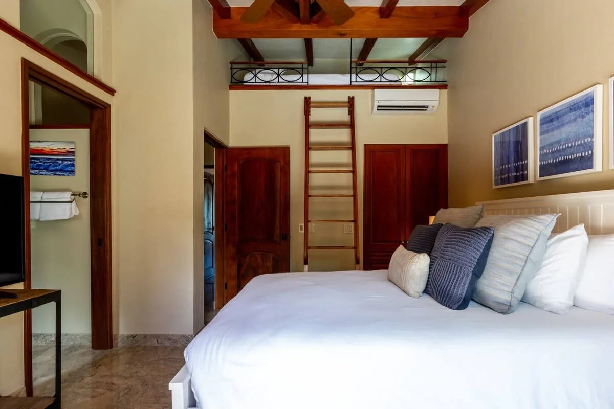 A bedroom with a large bed and exposed wooden ceiling beams.