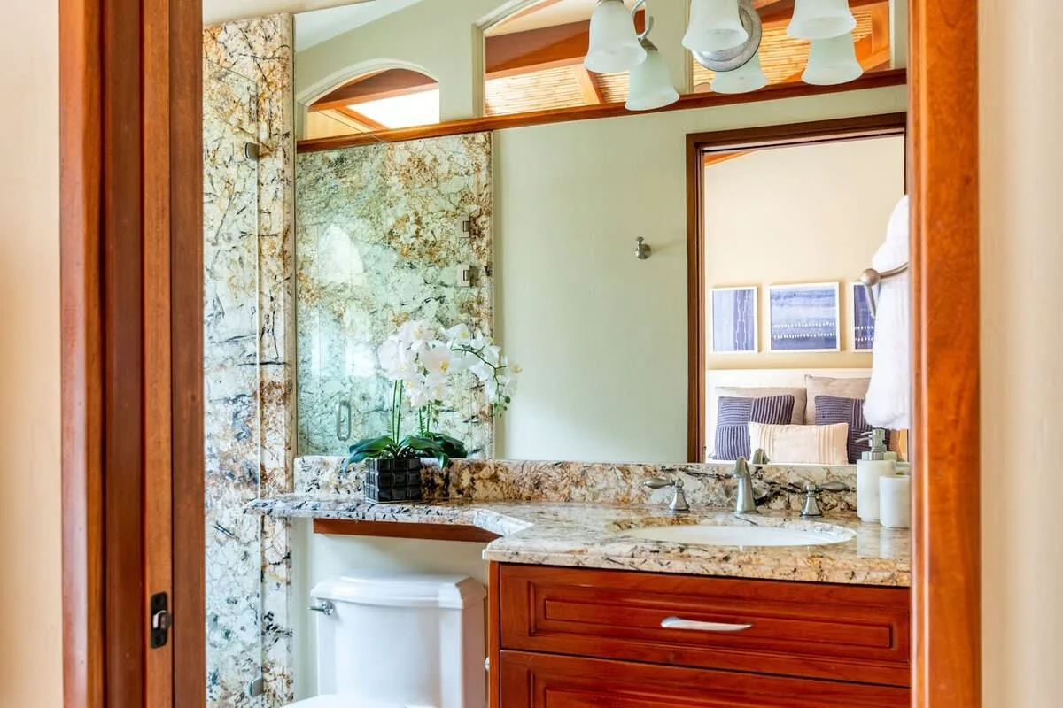 A bathroom vanity with a marble countertop and a large mirror.