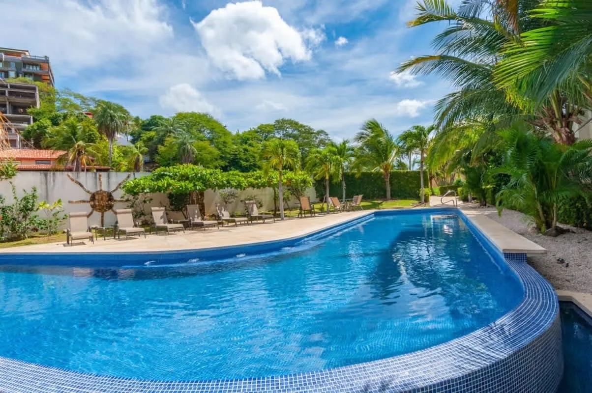 Shared amenity: An outdoor swimming pool bordered by lounge seating and tropical greenery.