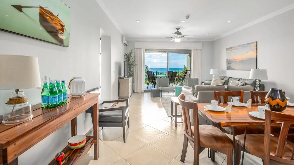 A bright open-plan living and dining room opens onto a balcony with ocean views.