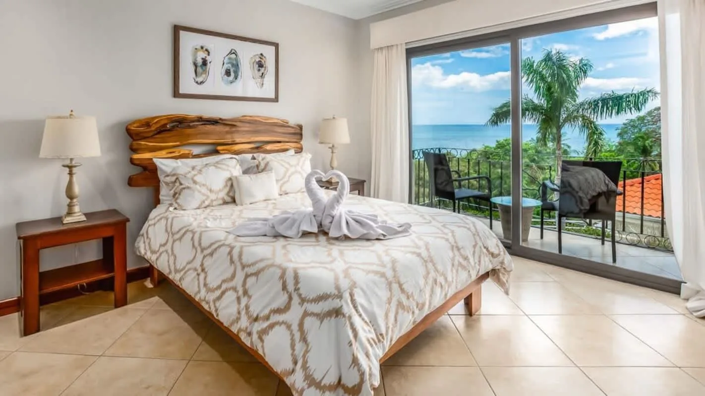 A bedroom with a bed beside sliding glass doors opening onto a balcony.