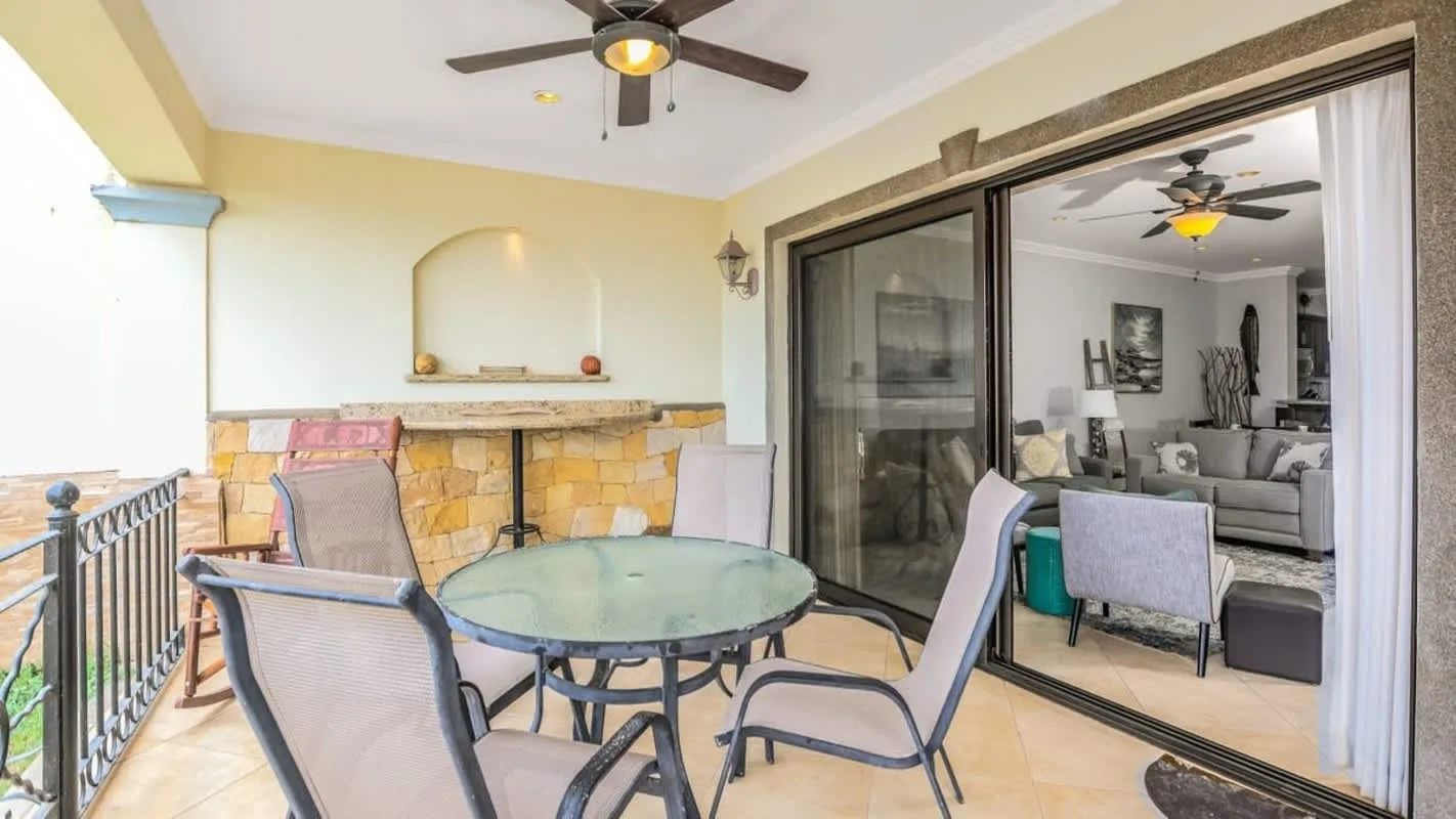 A patio seating area with a round glass table beside sliding glass doors.