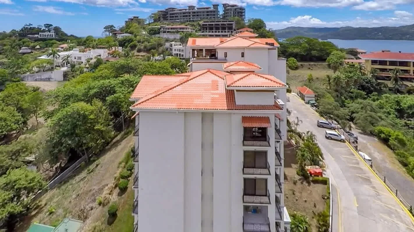 Shared amenity: Aerial view of a residential building beside a road and green hills.