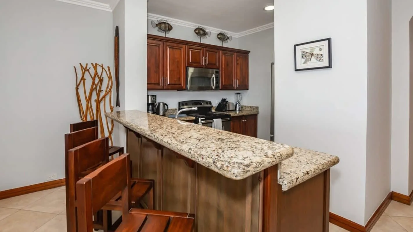 A kitchen with wooden cabinets and a long stone-patterned counter.