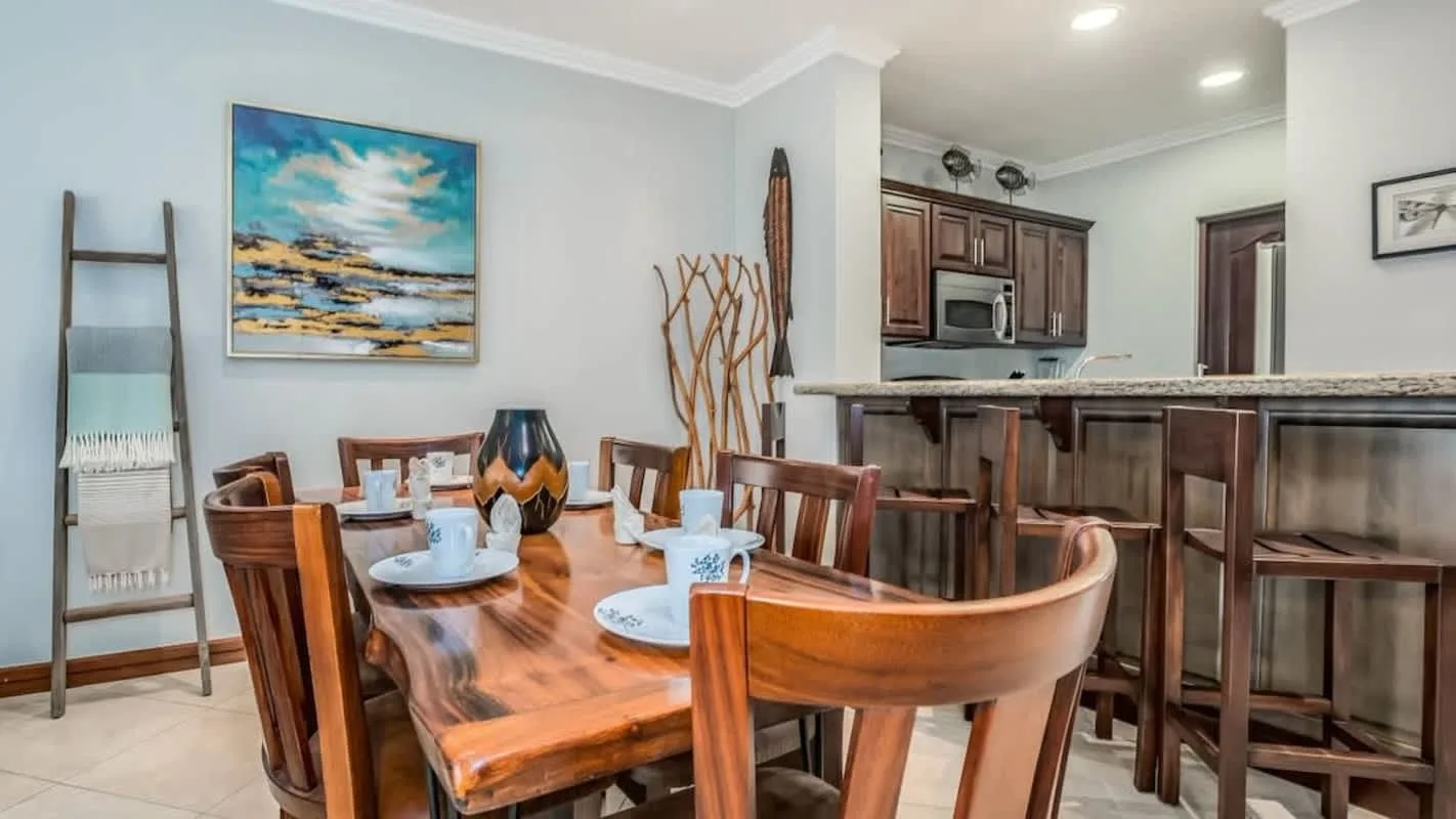 A dining area with a wooden table and chairs beside a kitchen counter.