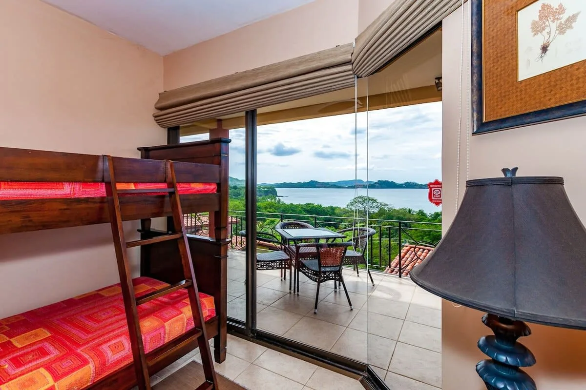 A bedroom with wooden bunk beds beside a glass door opening onto a balcony.