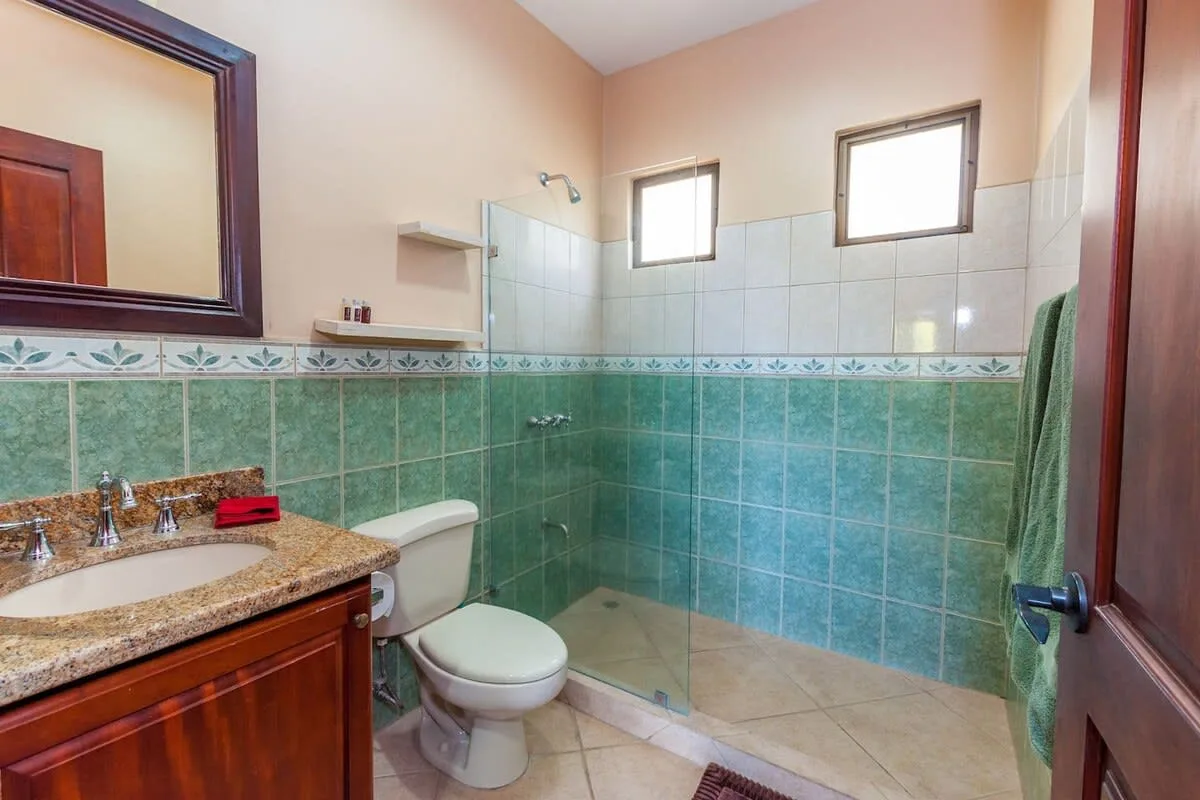 A tiled bathroom with a sink, toilet, and glass shower.