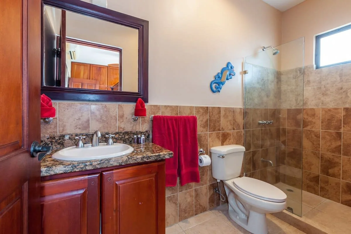 A bathroom with a vanity, toilet, and glass shower.