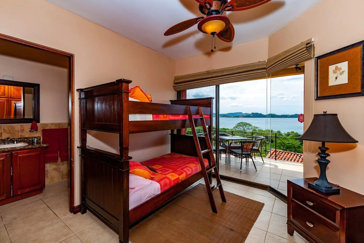 A bedroom with a wooden bunk bed and glass doors opening onto a balcony.
