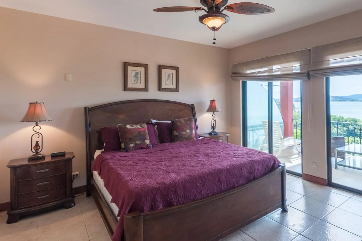 A bedroom with a large bed and glass doors opening onto a balcony.