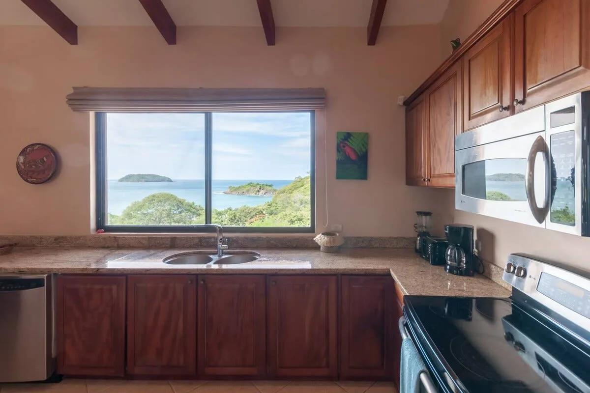 A kitchen with wooden cabinets and a large window overlooking the water.