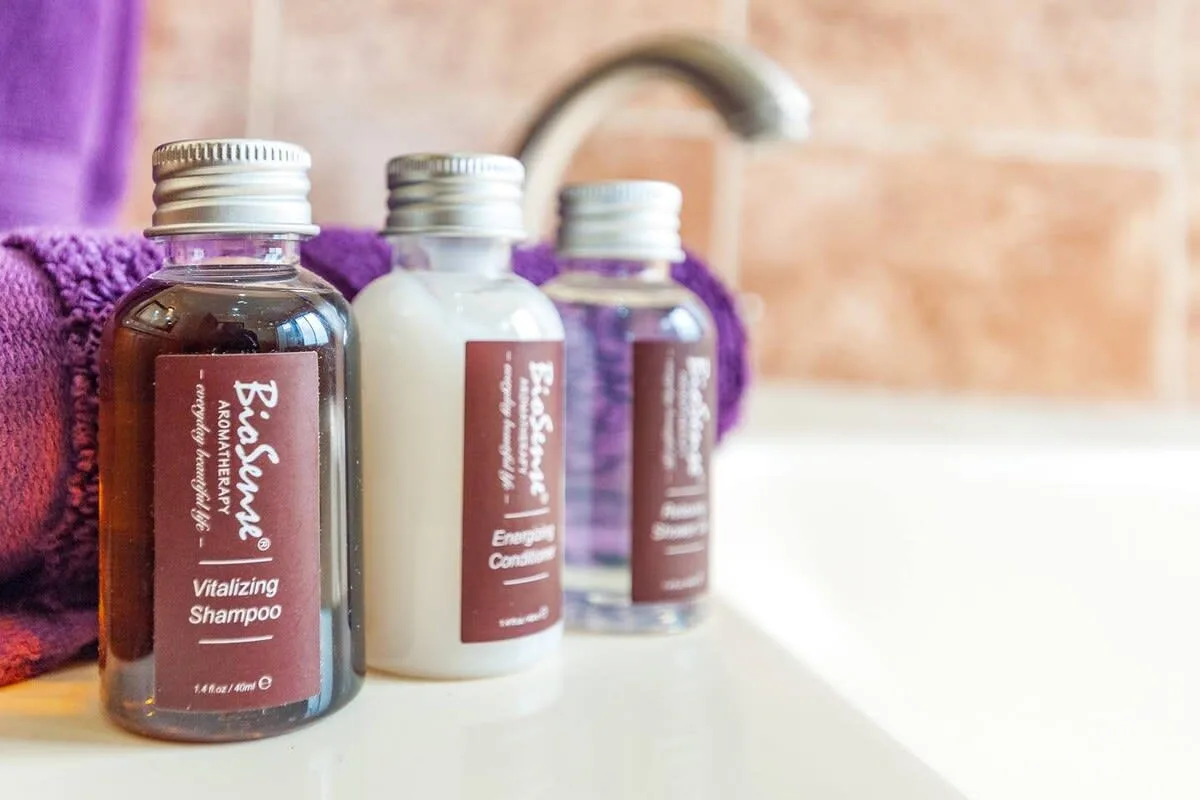 Bathroom toiletries sit beside a folded purple towel on a counter.
