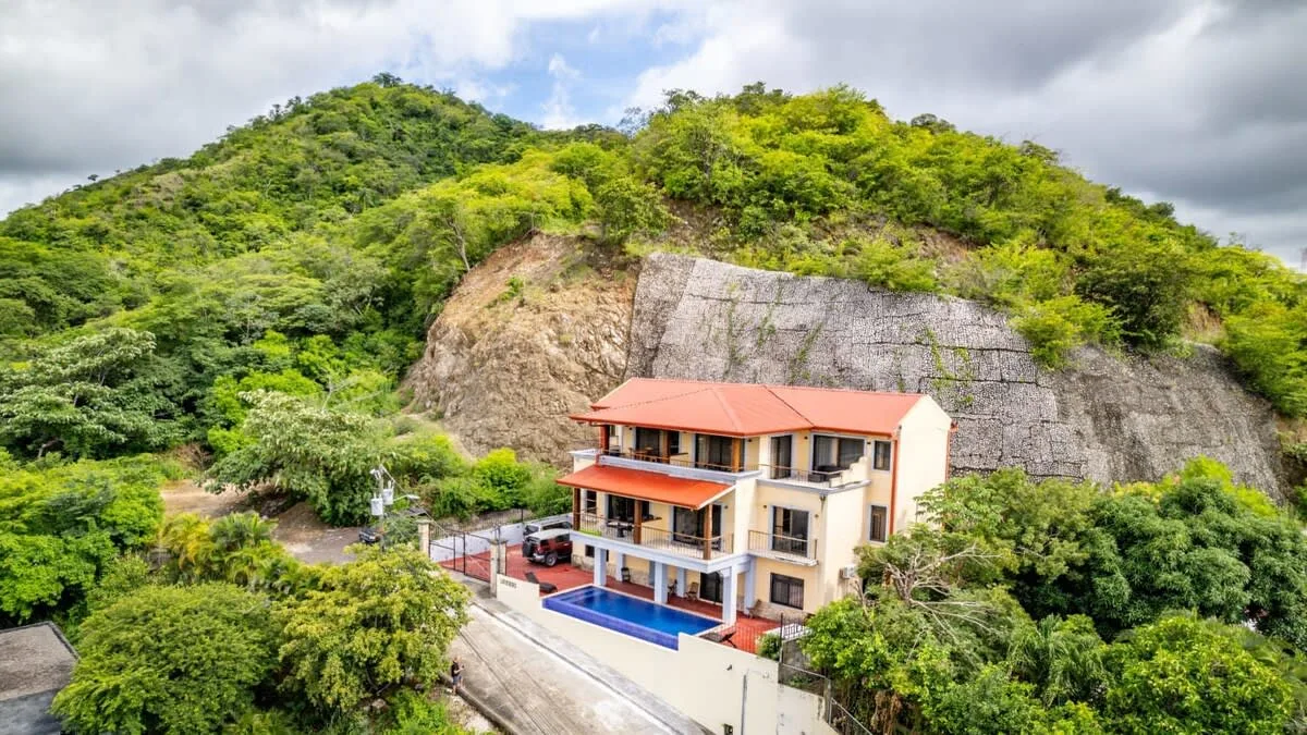 Shared amenity: A hillside building with a red roof stands beside a blue swimming pool.