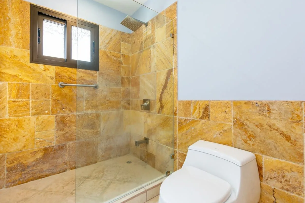 A tiled bathroom with a glass shower and a toilet.