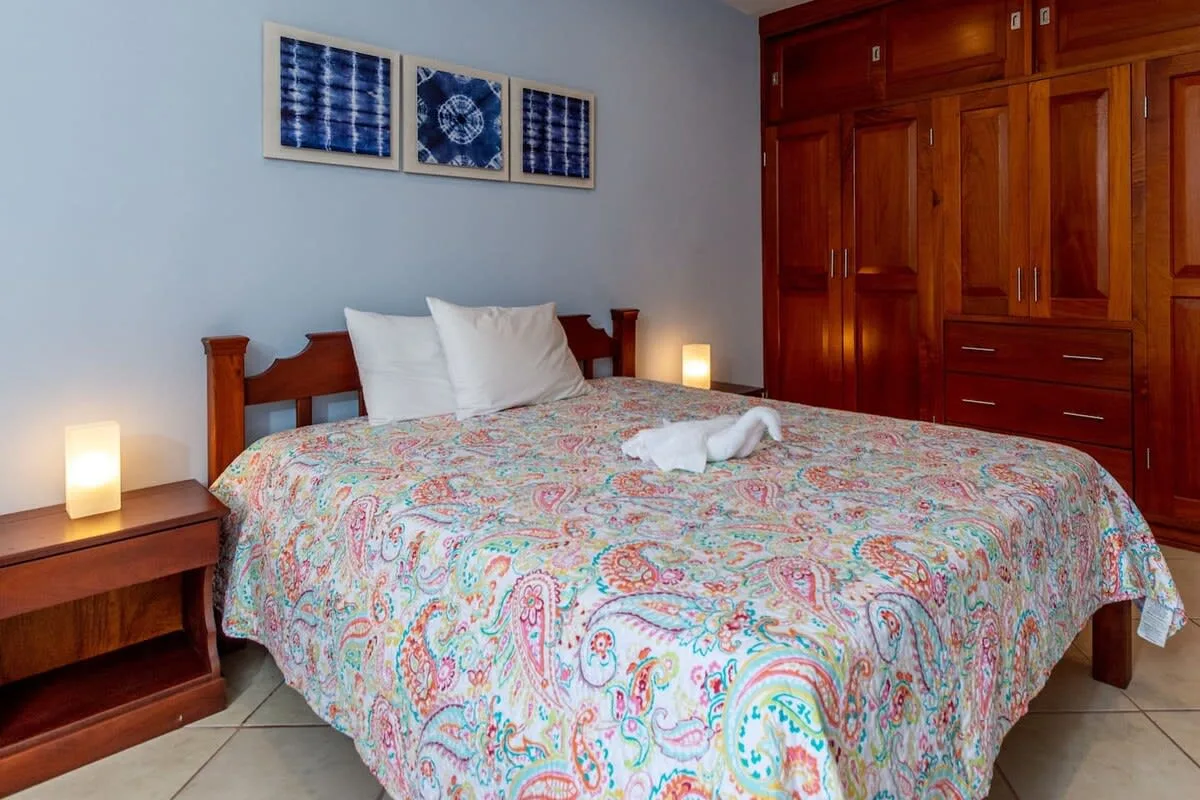 A bedroom with a bed covered by a colorful patterned bedspread.