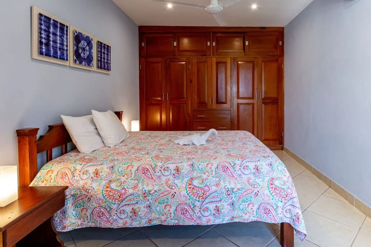 A bedroom with a bed covered in a colorful patterned bedspread.