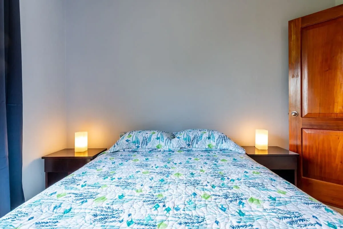 A bedroom with a bed covered in blue and green patterned bedding.