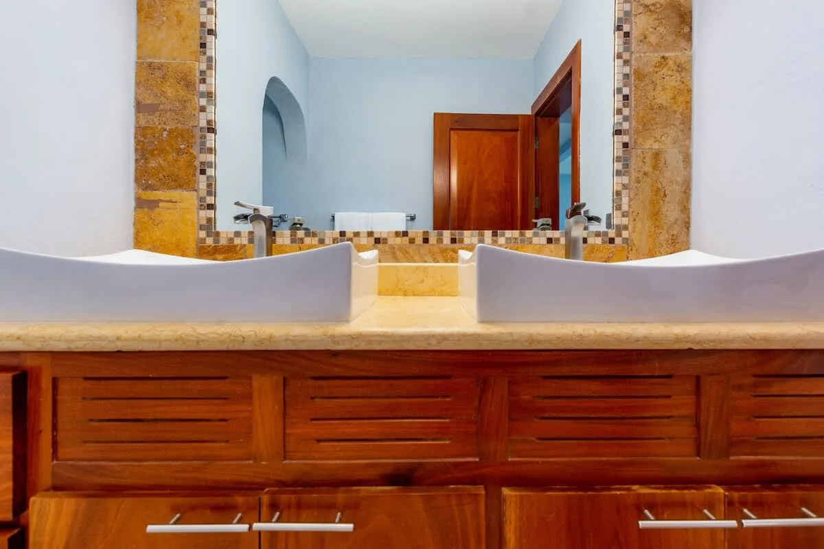 A bathroom vanity with two sinks and a large mirror above a wooden cabinet.