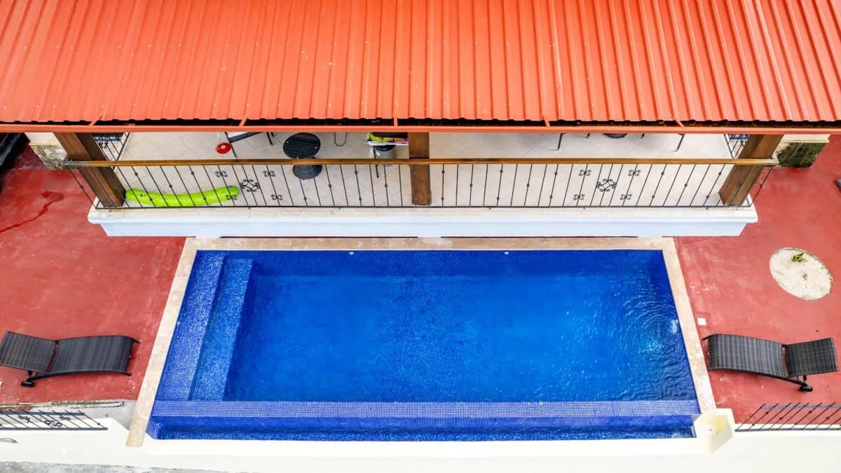 Shared amenity: A swimming pool sits beside a covered patio with lounge seating.