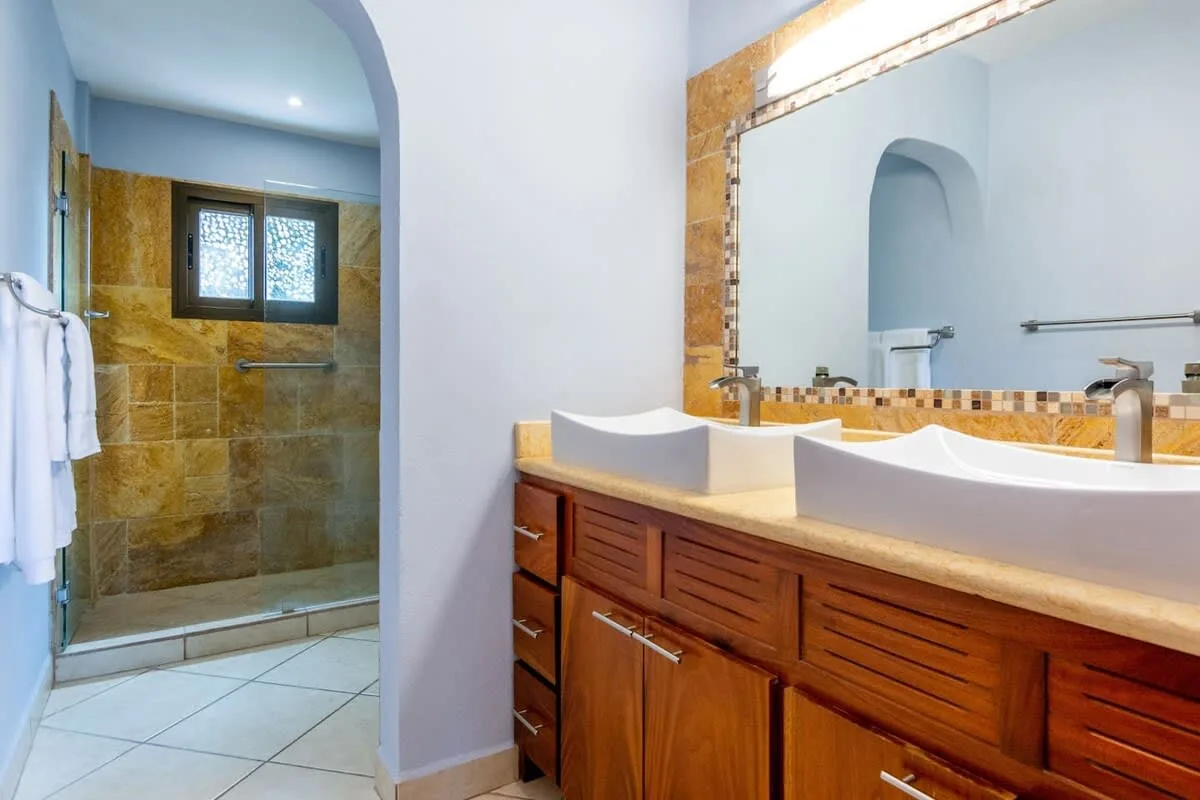 A bathroom with a long wooden vanity and a glass-enclosed shower.