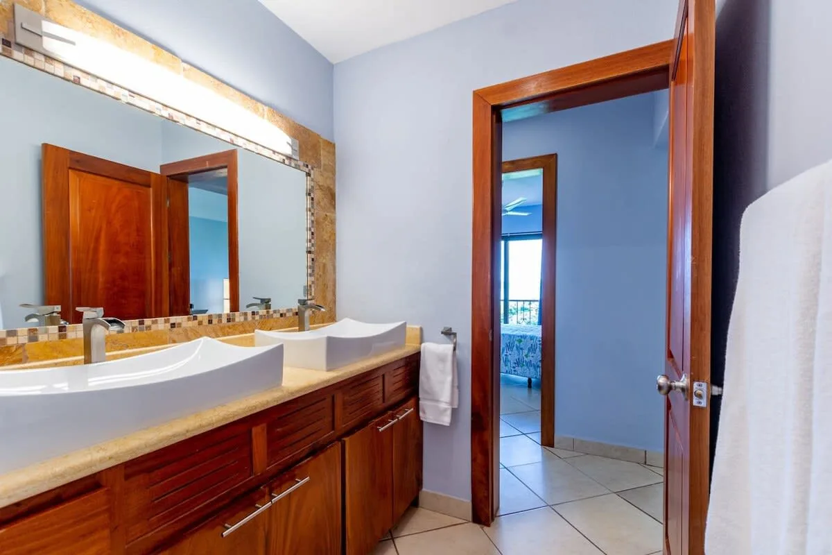 A bathroom vanity with a wide mirror sits beside an open doorway.