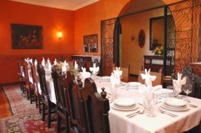 Un comedor con mesas largas preparadas con manteles blancos y cubiertos.