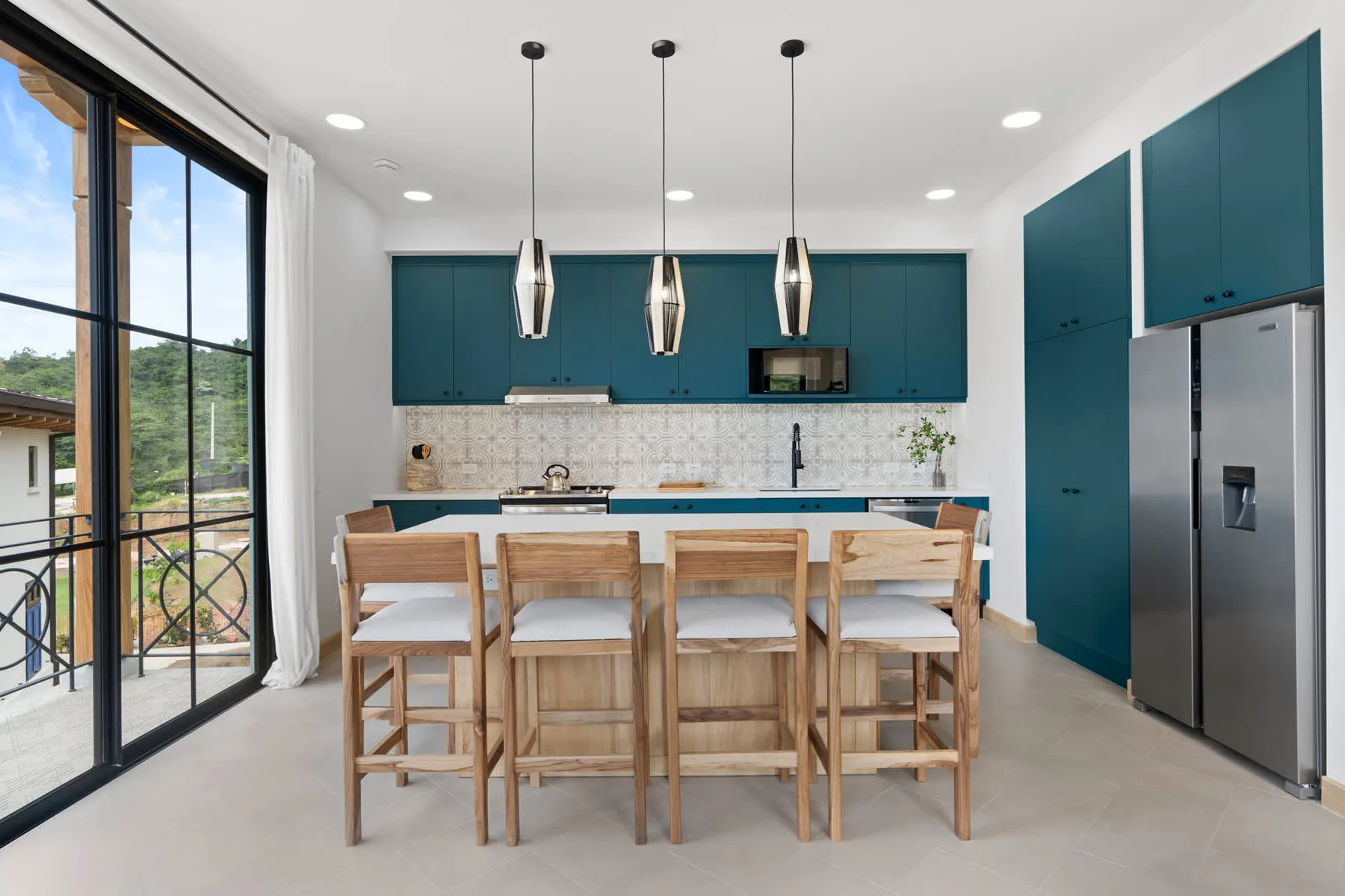 Una cocina moderna con gabinetes verde azulado, una isla larga y asientos de madera.