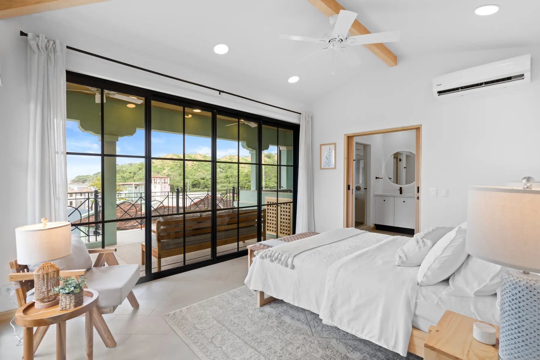 Un dormitorio luminoso con una cama grande junto a ventanas de piso a techo.