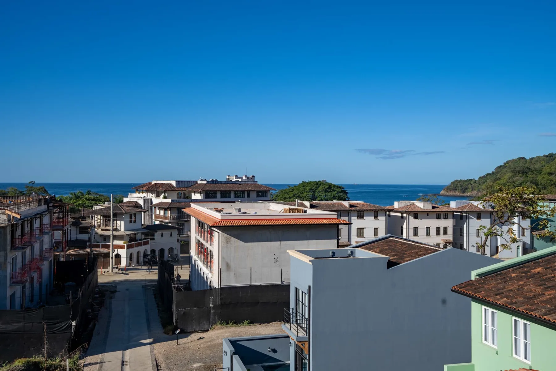 Un pueblo costero con edificios bajos, una calle y el océano a lo lejos.