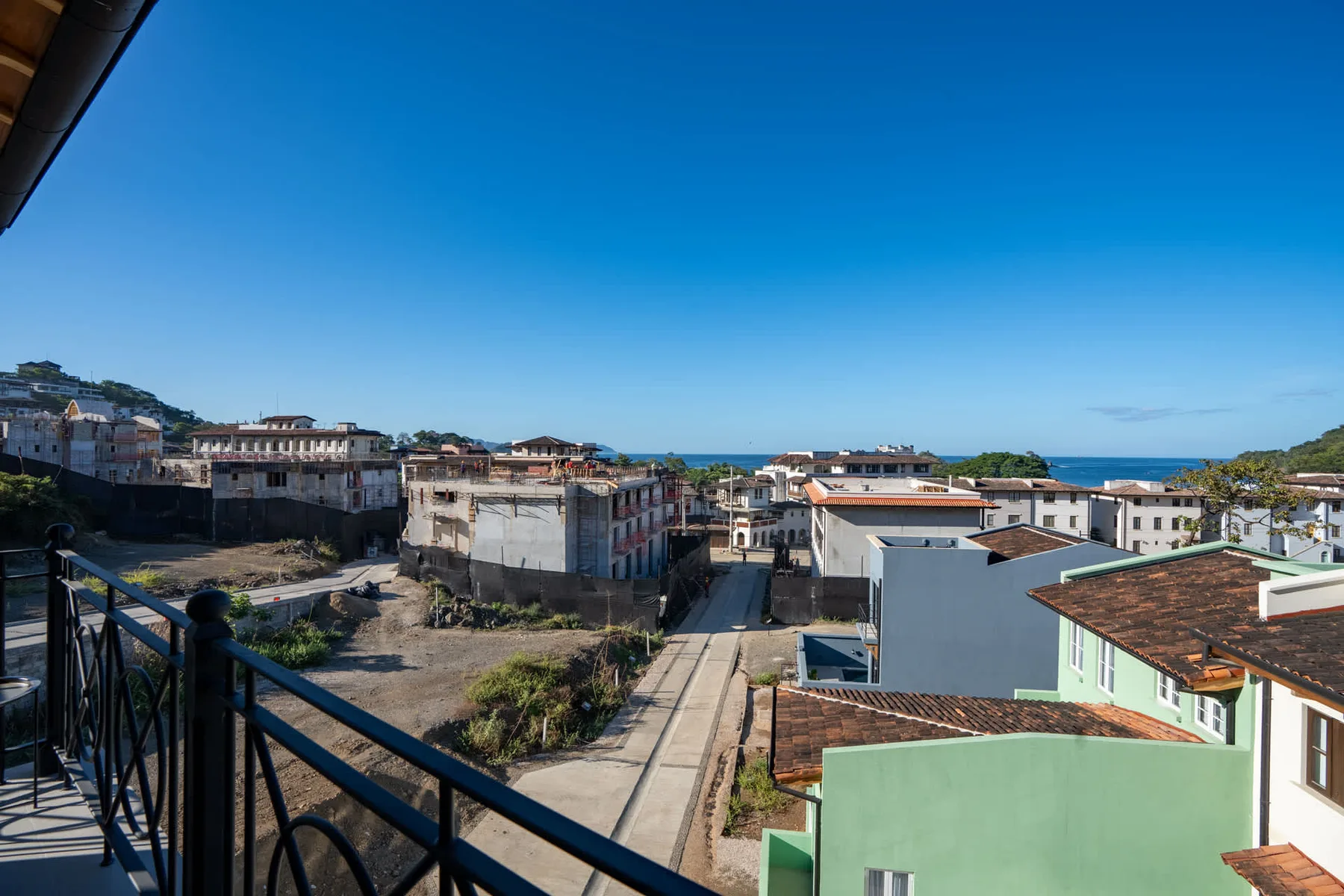 Un barrio costero con edificios bajos y el mar visible a lo lejos.