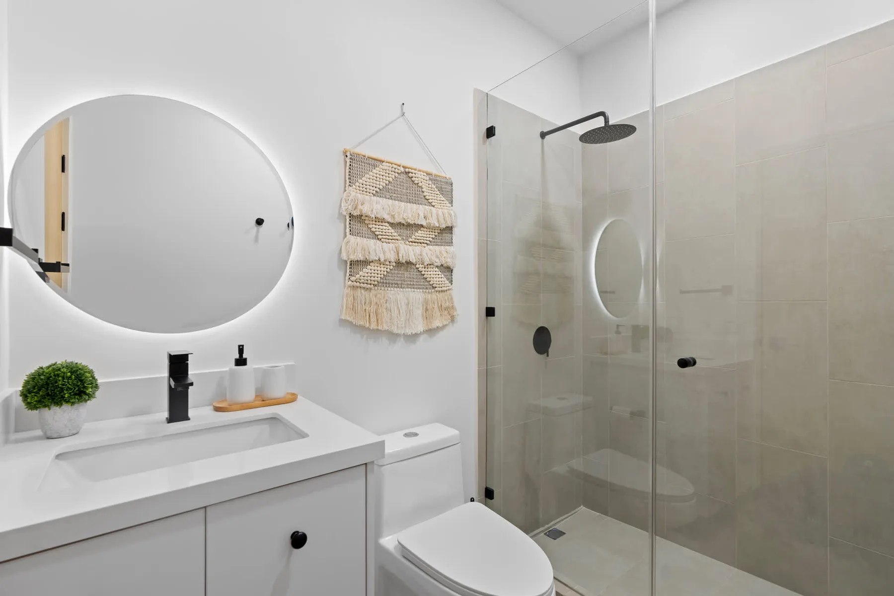 Un baño luminoso con lavabo, inodoro y ducha de vidrio.