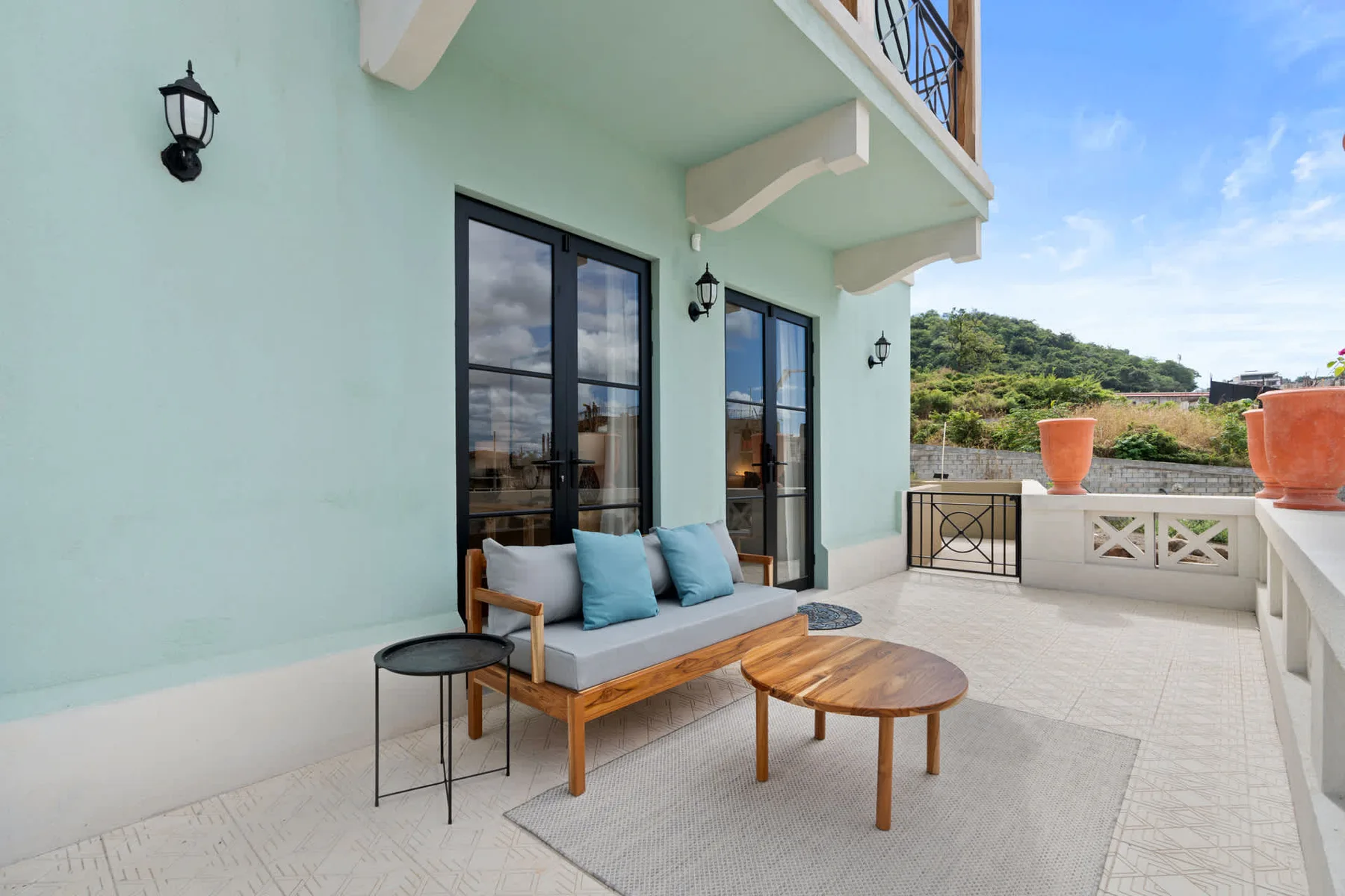 Una terraza al aire libre con asientos acolchados y una mesa baja de madera.