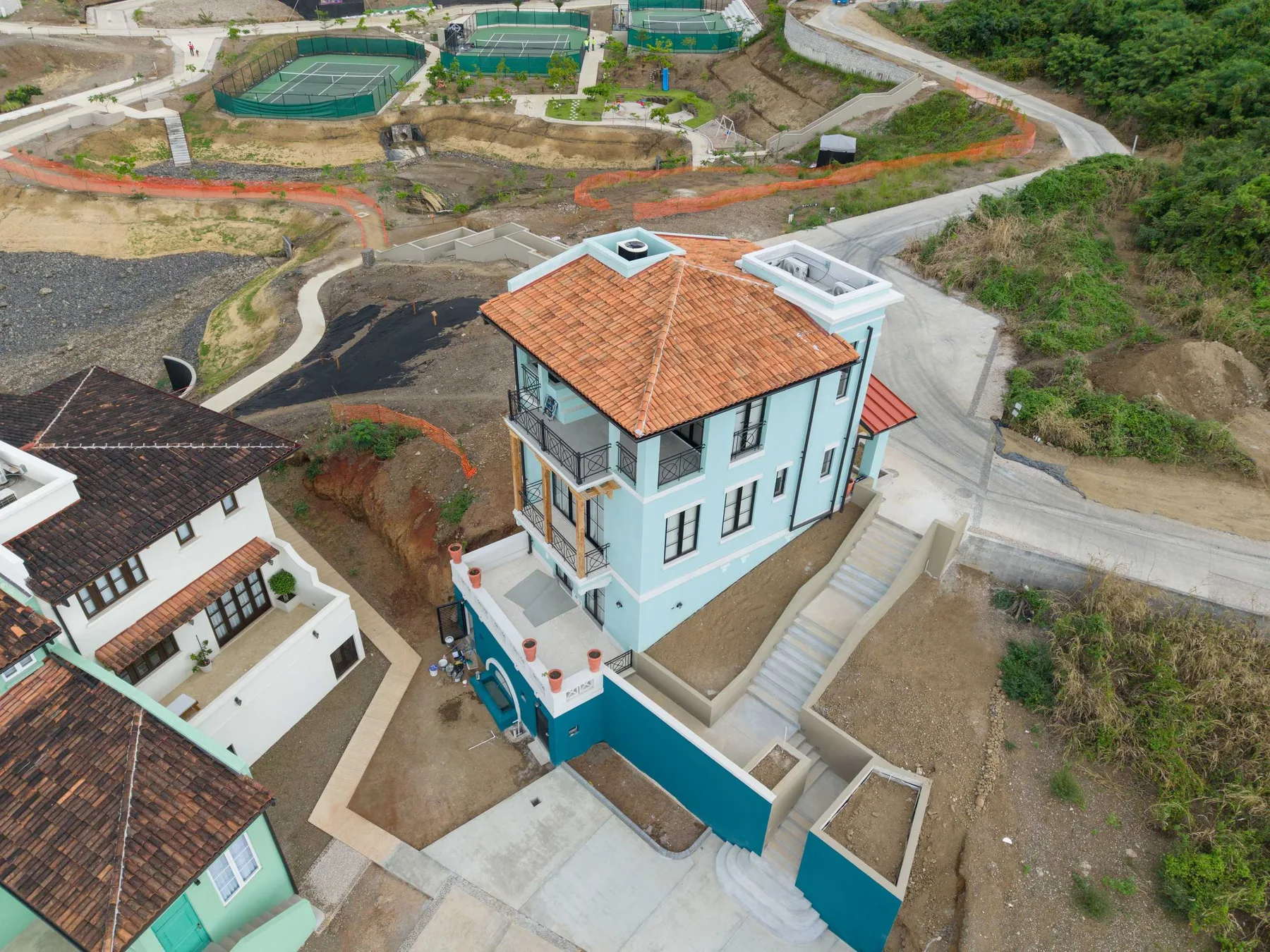 Vista aérea de una casa azul claro con techo de tejas color terracota.