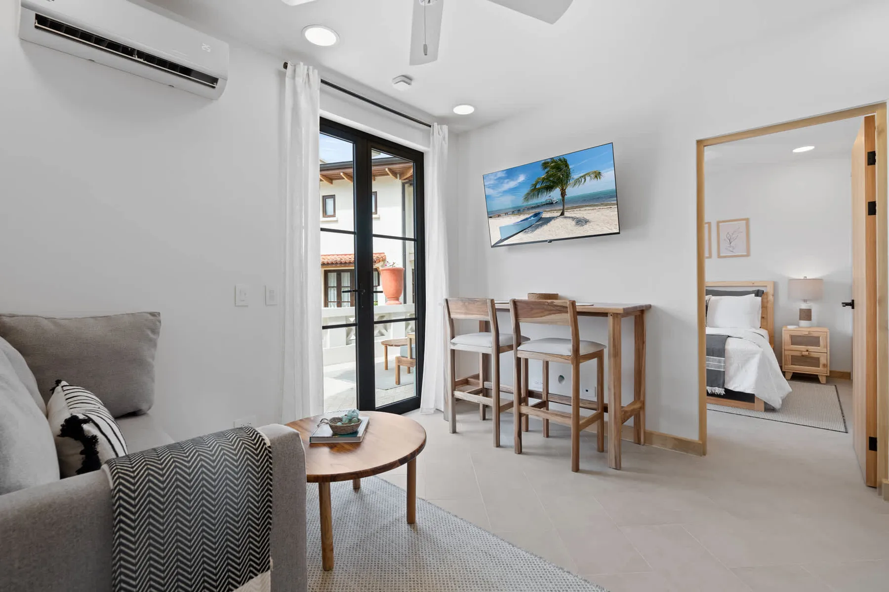 Una luminosa sala de estar con una pequeña mesa de comedor junto a puertas de vidrio al balcón.
