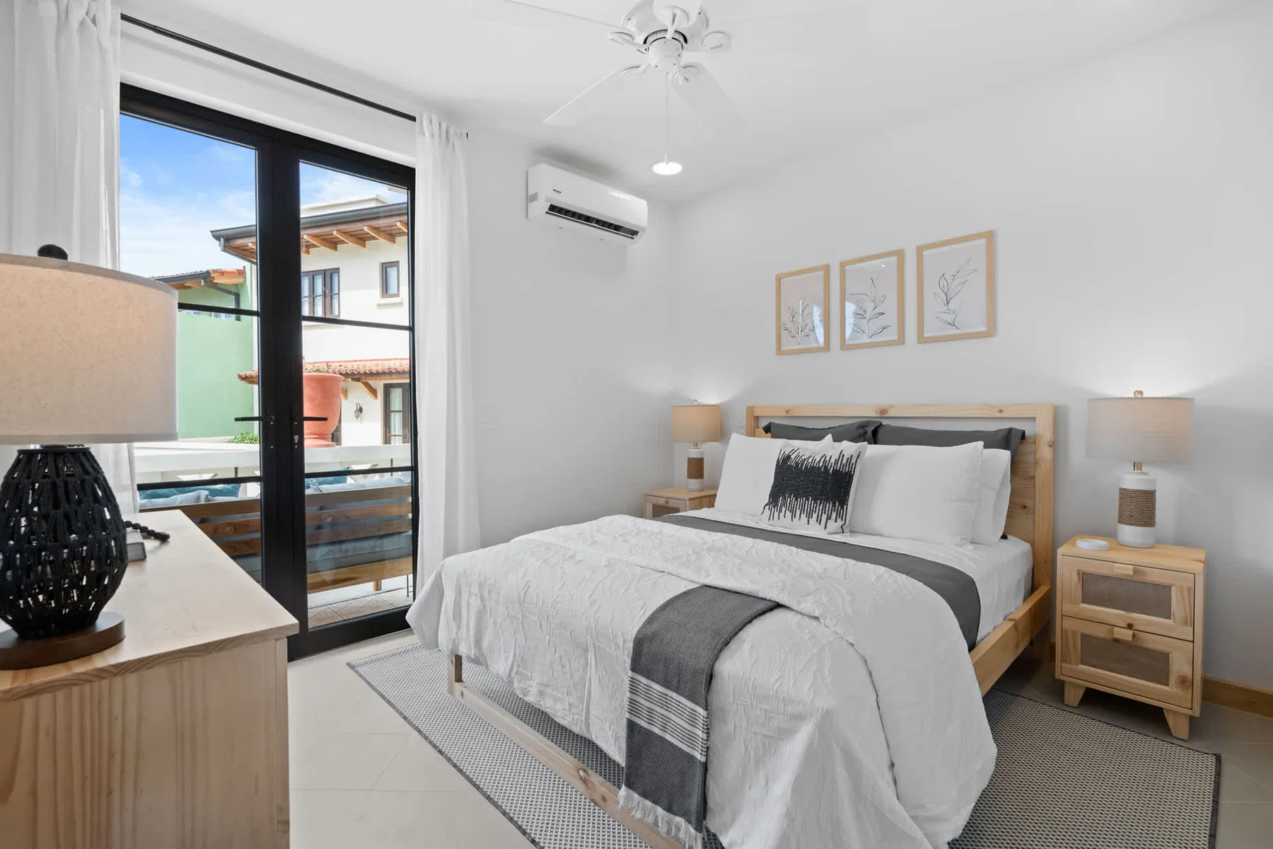 Un dormitorio luminoso con una cama bien tendida, mesitas de noche y una puerta corrediza de vidrio.