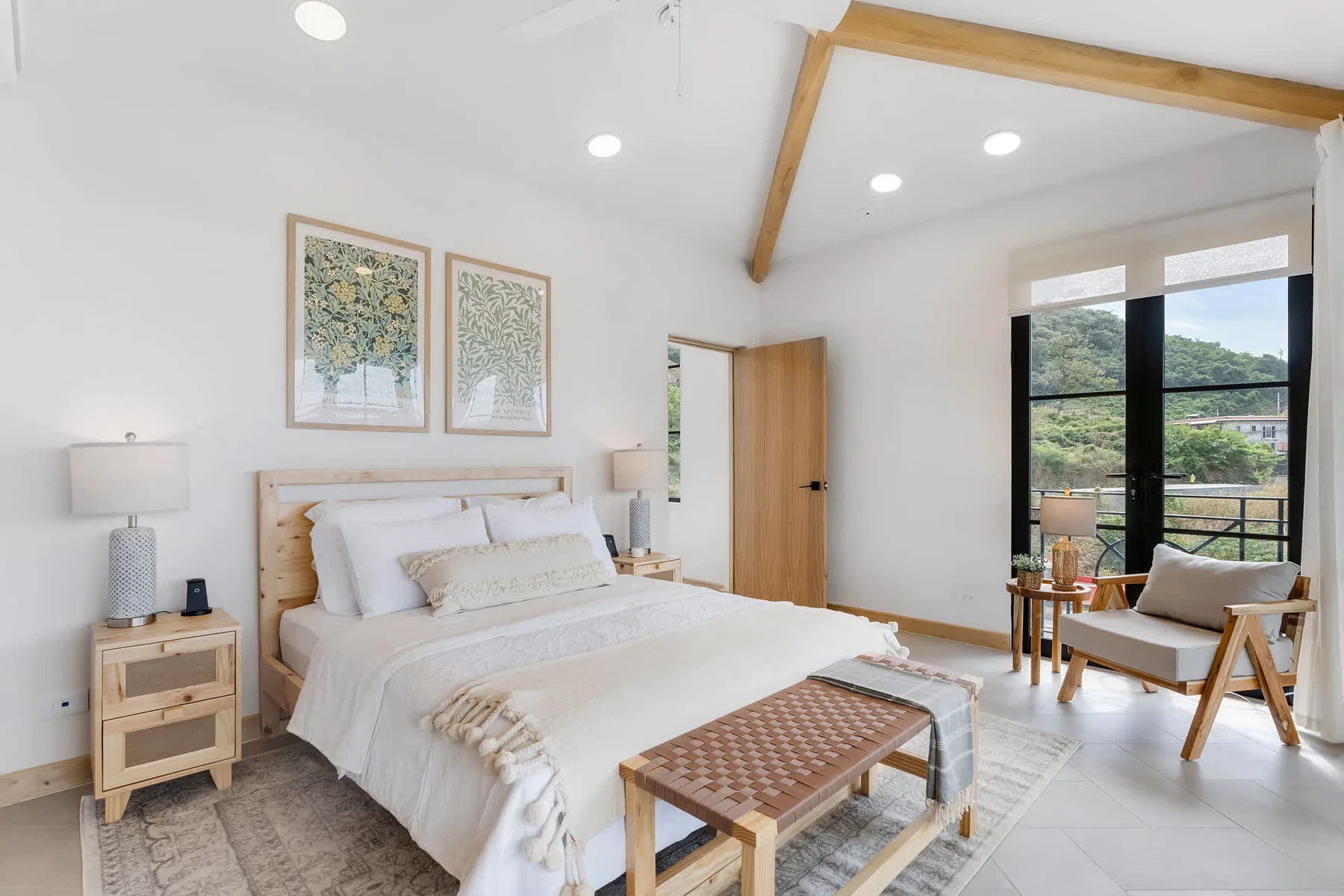 Un dormitorio luminoso con una cama bien hecha y una ventana grande con vistas a la vegetación.