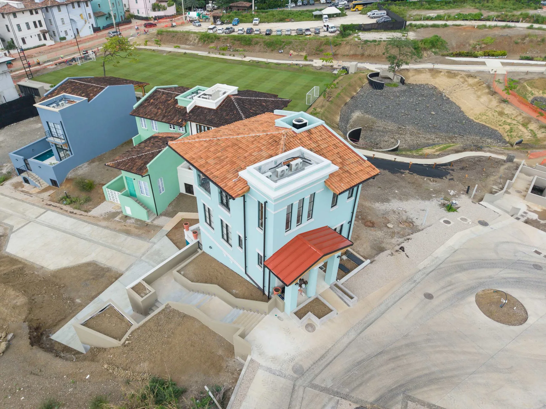 Vista aérea de una casa de reciente construcción junto a una carretera sin terminar y terreno desnudo.