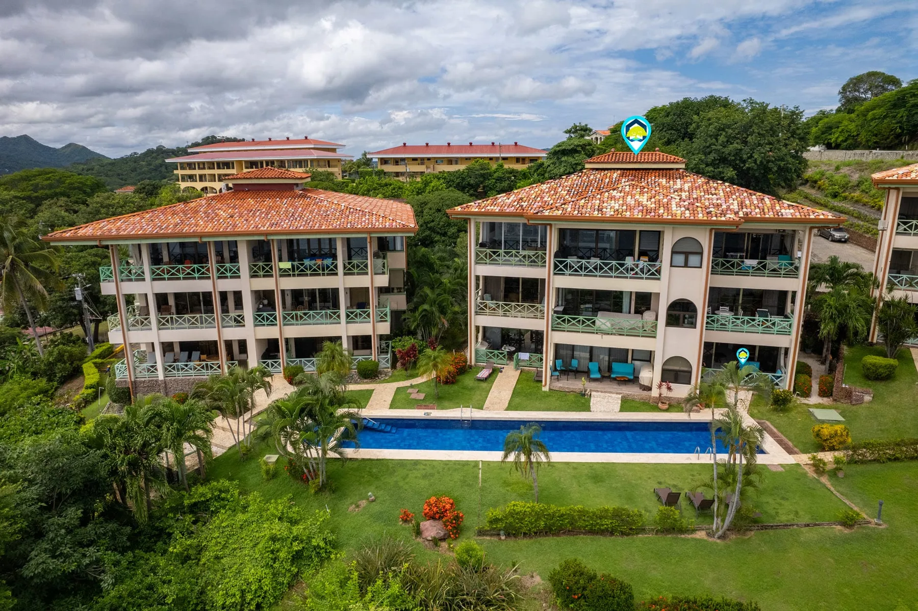 Shared amenity: Aerial view of resort buildings surrounding a long outdoor swimming pool.