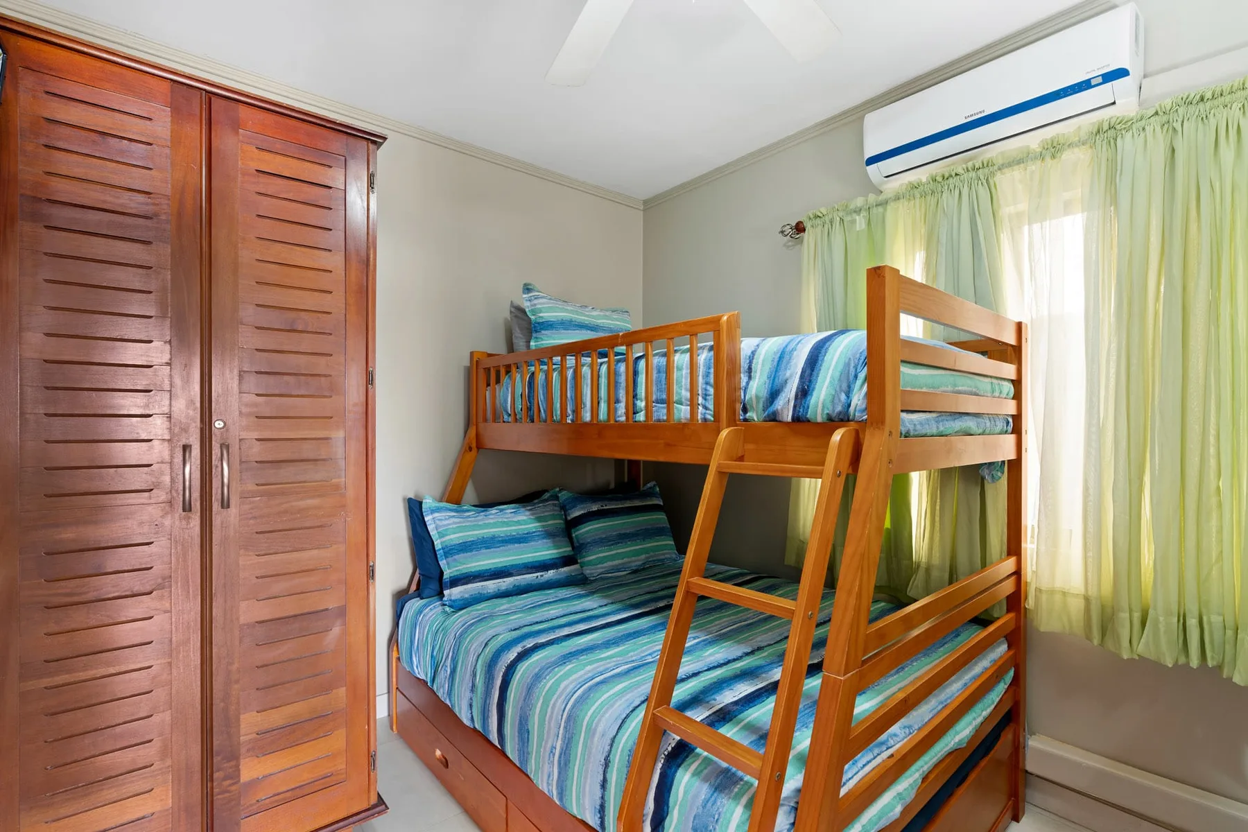A bedroom with a wooden bunk bed and striped blue bedding.