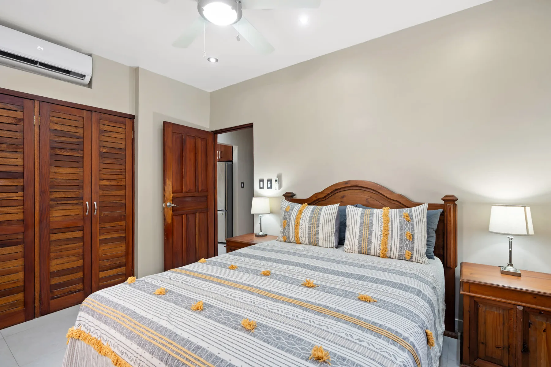 A bedroom with a wooden bed, patterned bedding, and a wardrobe.