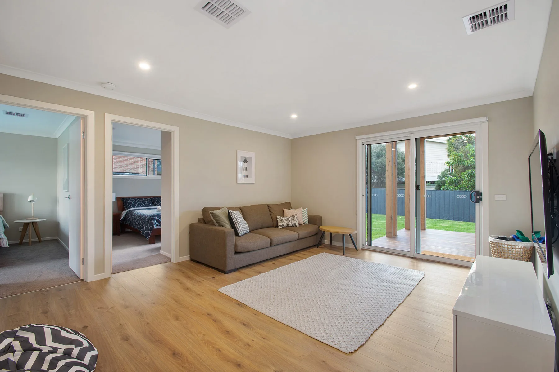 A bright living room with a sofa, area rug, and sliding glass doors.