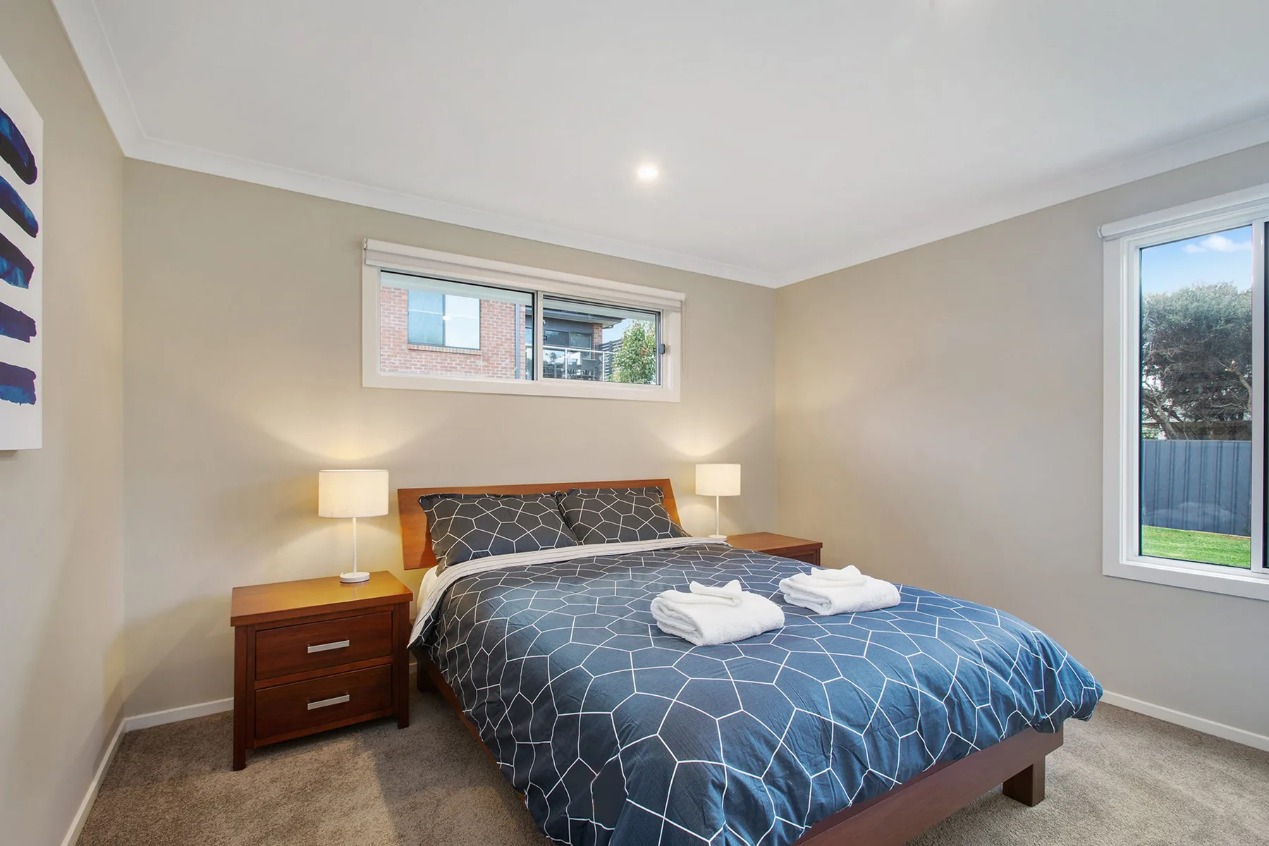 A bedroom with a bed dressed in blue patterned bedding and bedside lamps.